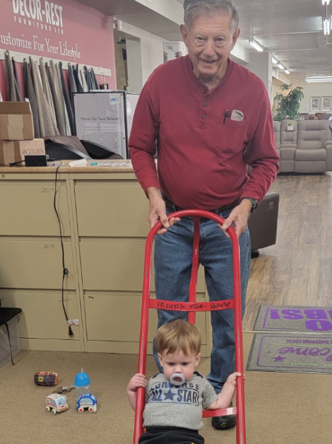 Meyers family patriarch smiling while playfully pushing a toddler on a hand truck inside the showroom.